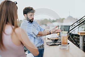 A couple of young business partners are discussing new ideas and growth strategies over coffee at an urban cafe on a