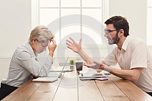 Couple of young colleagues arguing at office