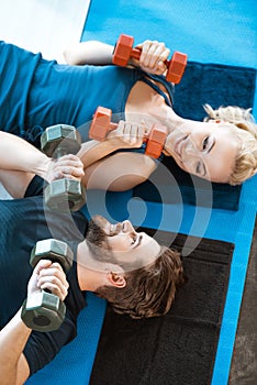 Couple of young fitness people exercising with dumbbells