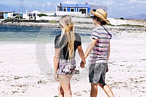 Couple of young girl and boy in tourist leisure activity walking on the beach in love and relationship. Happy people enojy