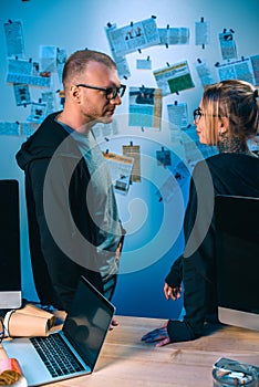 couple of young hackers standing near desk with computers