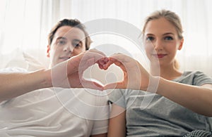 Couple young in love making heart shape with hands in bedroom