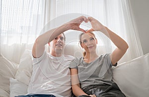 Couple young in love making heart shape with hands in bedroom