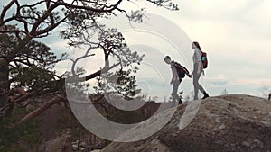 A couple of young lovers with backpacks holding their hands and climbing down the high stoned mountain hill. Tourism