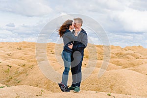 A couple of young lovers a man and a woman in the desert with sand dunes of bizarre shape
