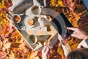 Couple of Coman and woman having morning breakfast in the autumn garden with colorful maple leaves. cup of coffee, marshmallow jam photo