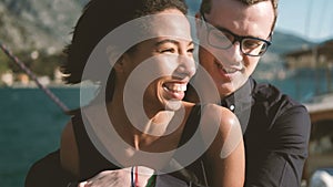 Couple of young people stand hugging on yacht kissing one another