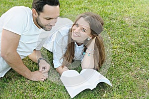 Couple of young students studing on the grass by the campus