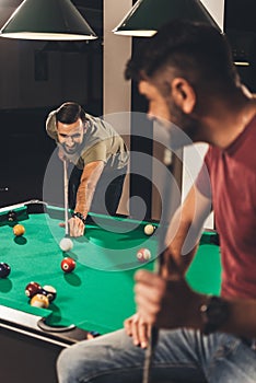 couple of young successful handsome men playing in pool