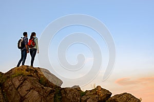 Couple of Young Travelers Standing on the Top of the Rock at Summer Sunset. Family Travel and Adventure Concept