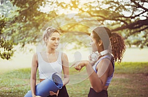 Couple young woman holding yoga mat and talking together at public park,Happy and smiling,Healthy and lifestyle concept