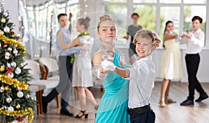 Couples dancing - teenagers in festive clothes dance the Viennese waltz near Christmas tree