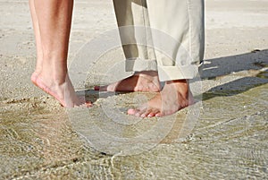 Couples feet standing on beach