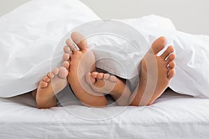 Couples feet sticking out from under duvet