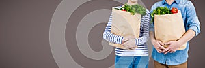 Couples mid sections with grocery bags against brown background