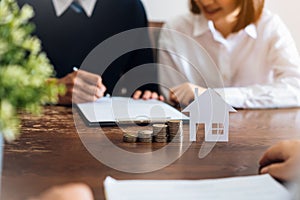 Couples signed a contract to buy a house from the broker. Coin to stack money and model houses placed on the table. photo