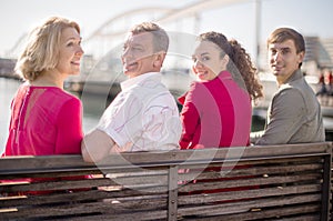 Couples of tourists sitting on bench in port European city