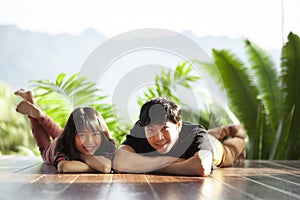 Couples of younger asian man and woman lying with happiness face on home wood floor