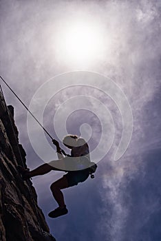 Coraje de la roca alpinista. silueta de mujer joven rappel abajo la roca 