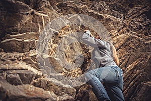 Courage woman achieving her goal climbing up on rock