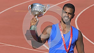 Courageous sportsman kissing trophy cup, celebrating triumph and recognition