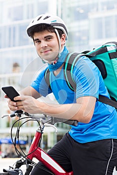 Courier On Bicycle Delivering Food In City Using Mobile Phone