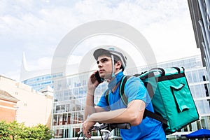 Courier On Bicycle Delivering Food In City Using Mobile Phone