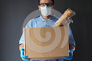 Courier with a big cardboard box with bread. Food Delivery Service.