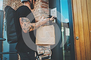 Courier city delivery food service at home. Tattooed Man courier delivered the order no name bag with food
