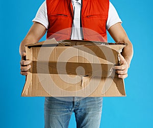 Courier with damaged cardboard box on background, closeup. Poor quality delivery service