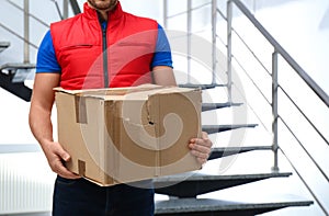 Courier with damaged cardboard box indoors. Poor quality delivery service