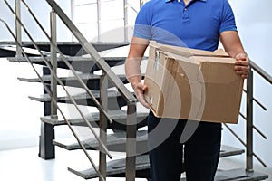 Courier with damaged cardboard box indoors. Poor quality delivery service