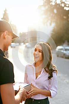 Courier Delivering Package To Woman. Client Receiving Box