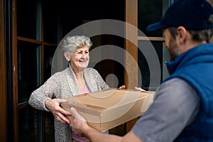 Courier delivering parcel to senior woman, corona virus and quarantine concept.