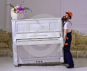 Courier delivers furniture, move out, relocation. Heavy loads concept. Loader moves piano instrument. Man with beard