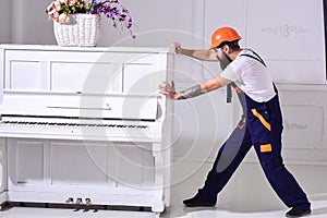 Courier delivers furniture, move out, relocation. Heavy loads concept. Loader moves piano instrument. Man with beard