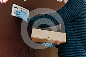 Courier, delivery caucasian man in protective mask safely delivers online purchases in brown box to the door during the