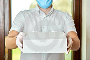 Courier, delivery man in protective mask and medical gloves delivers takeaway food.