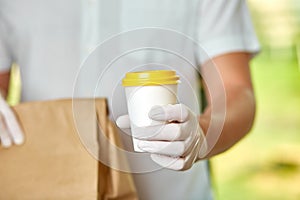 Courier, delivery man in protective mask and medical gloves delivers takeaway food and coffee.