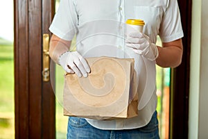 Courier, delivery man in protective mask and medical gloves delivers takeaway food. Delivery service under quarantine, disease out