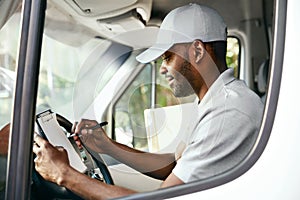 Courier. Delivery Man Reading Addresses Sitting In Delivery Van