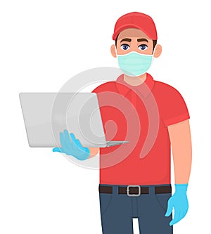 Courier or delivery person in mask and gloves showing laptop computer. Man holding PC. Corona virus epidemic outbreak. Online