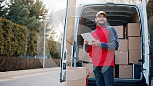 Courier with digital tablet delivering package. Mailman in front the van