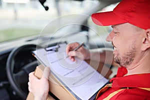 Courier driver fills in delivery receipts in car