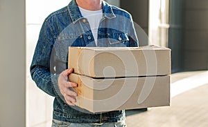 Courier in a face mask with a box in his hands. Portrait from the waist up. Delivery man concept.. Outdoor photo