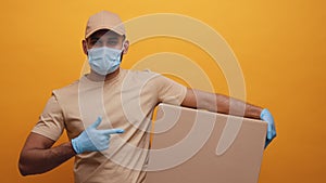 Courier with face mask holding backage and pointing finger into it
