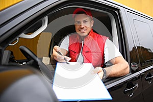 Courier giving clipboard with documents out of car window outdoors