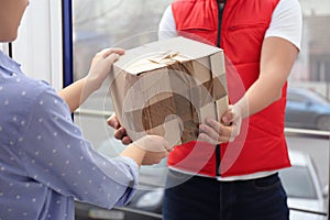 Courier giving damaged cardboard box to client in doorway. Poor quality delivery service