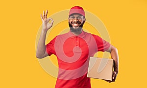 Courier Guy Holding Cardboard Box Gesturing Okay On Yellow Background