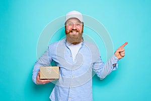 Courier with hat is happy to deliver a carton box and indicates something